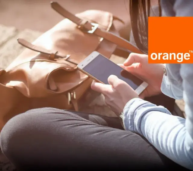 Kobieta z telefonem w dłoni, obok brązowa torba. Idealny dzień na środy z Orange.