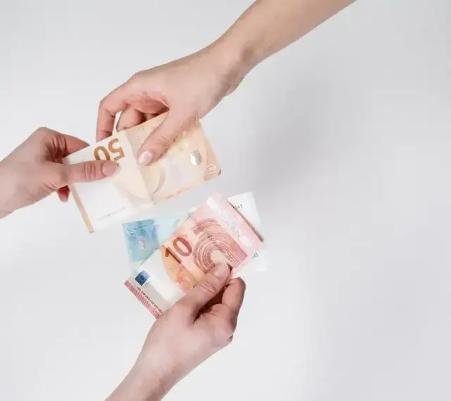 Dwie ręce przekazują sobie banknoty euro. To popularna waluta austrii, używana do codziennych transakcji.