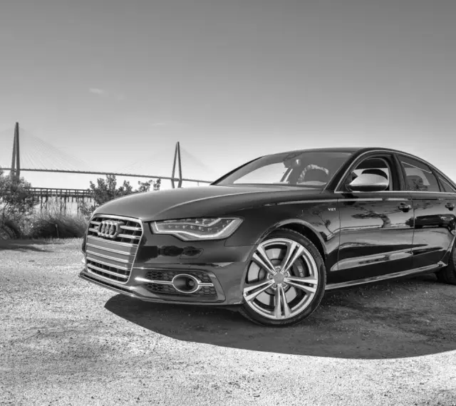 Elegancki czarny Audi S6 C7 z charakterystycznym grillem i felgami, zaparkowany na tle mostu wiszącego.