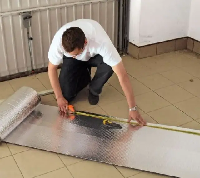 Mężczyzna mierzy materiał do ocieplenia bramy garażowej.