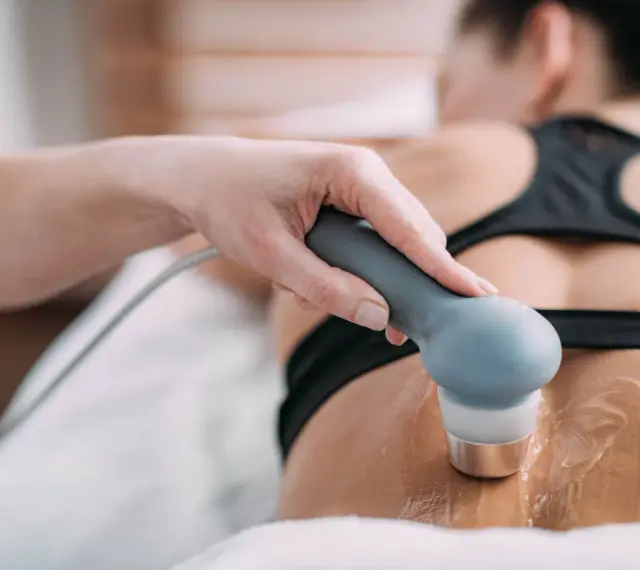 Therapeutin führt Ultraschall Physiotherapie am Rücken einer Patientin durch. Gel auf der Haut für die Behandlung.