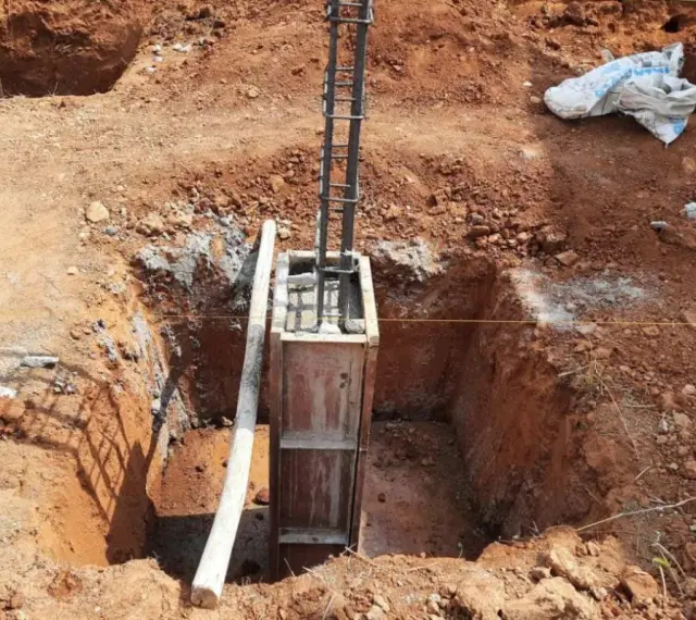 Wykop pod fundament słupowy, zbrojenie i szalunek gotowe do zalania betonem.