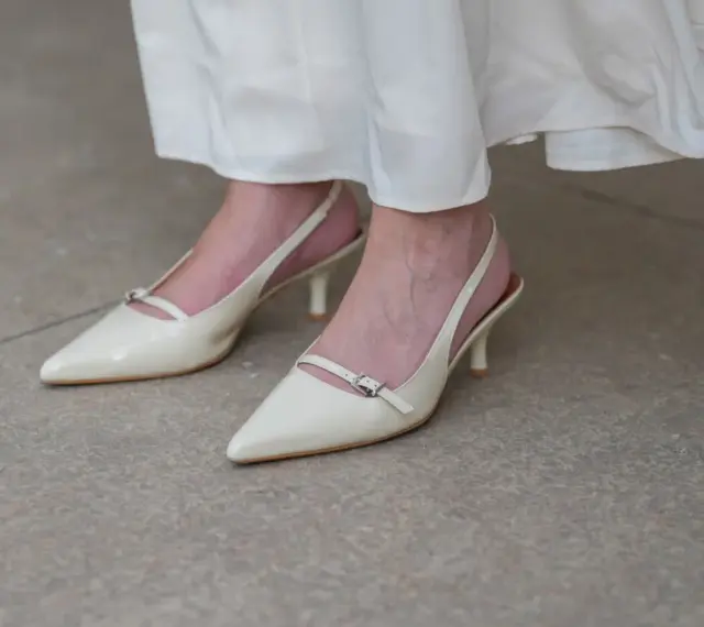 Eleganckie, kremowe szpilki z paskiem na pięcie, idealne do letnich sukienek. Niewidoczne skarpetki do szpilek zapewniają komfort.