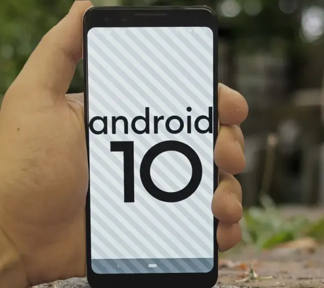 Dłoń trzyma smartfon z logo android 10 na ekranie.