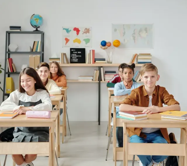 Uczniowie siedzą w ławkach w klasie, która wygląda jak szkoła średnia w Niemczech.