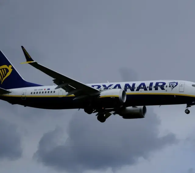 Samolot Ryanair z logo na ogonie leci na tle pochmurnego nieba. Może to być symbol zmiany nazwiska, gdy pasażerowie zmieniają swoje dane przed podróżą.