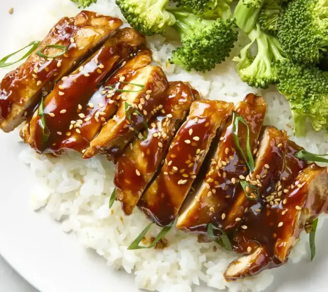 Pyszny kurczak w marynacie teriyaki, podany z ryżem i brokułami. Posypany sezamem i szczypiorkiem.