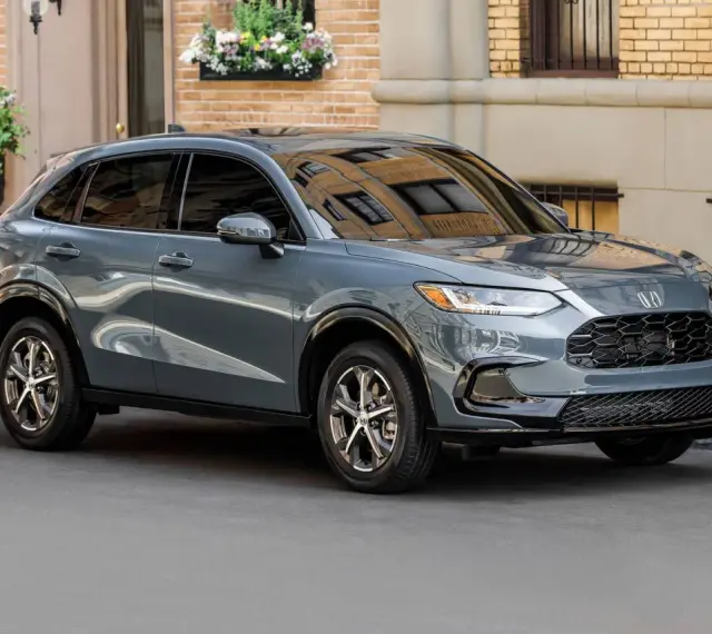 Elegancki, szary SUV Honda HR-V stoi na ulicy przed budynkiem z cegły.