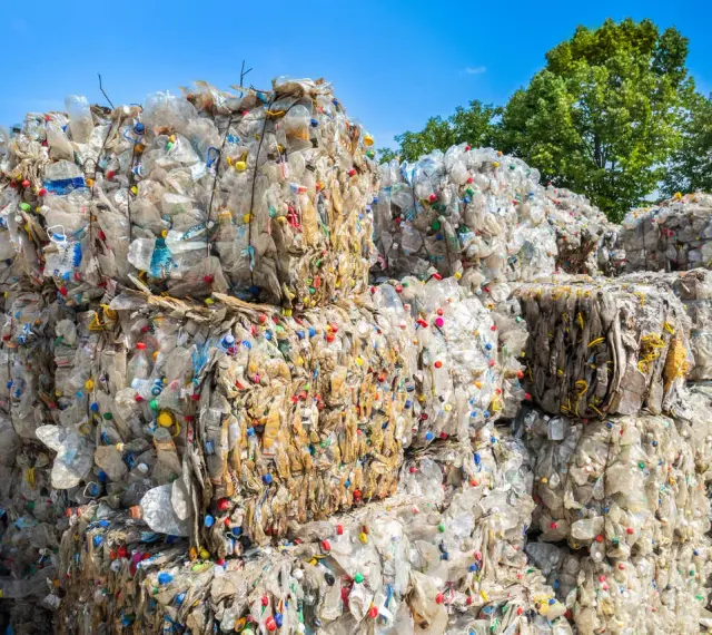 Ogromne bele sprasowanych plastikowych butelek tworzą krajobraz wysypiska śmieci. Kolorowe nakrętki dodają im niepokojącego uroku.