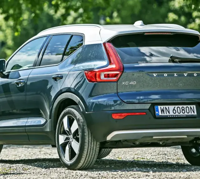 Tylna część ciemnoszarego Volvo XC40 z białym dachem, zaparkowanego na żwirowej drodze. Sprawdź aktualną volvo xc40 cena.