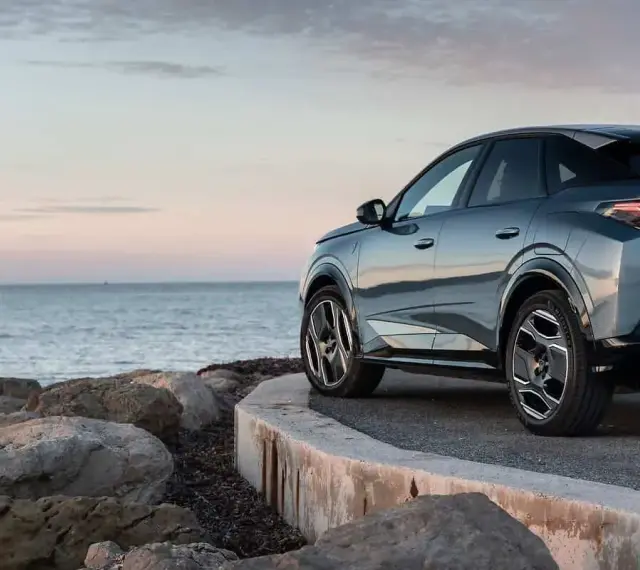 Nowy Peugeot 3008 hybryda na tle spokojnego morza i skalistego wybrzeża.