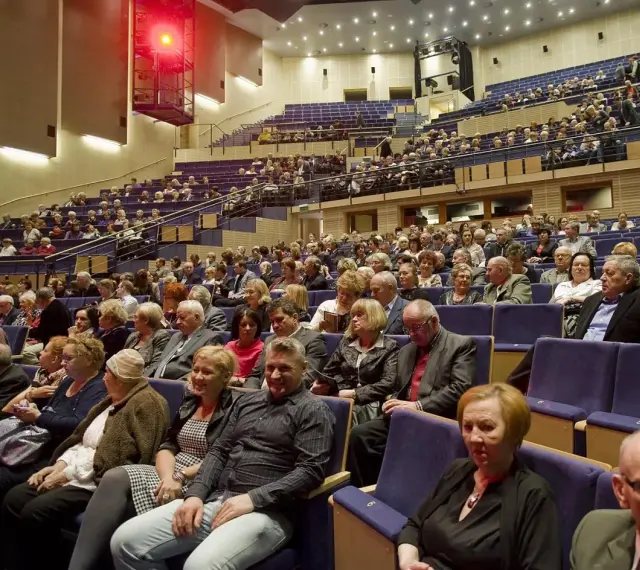 Widownia filharmonii, ludzie w eleganckich strojach. Jak się ubrać do filharmonii mężczyzna? Garnitur lub marynarka to dobry wybór.