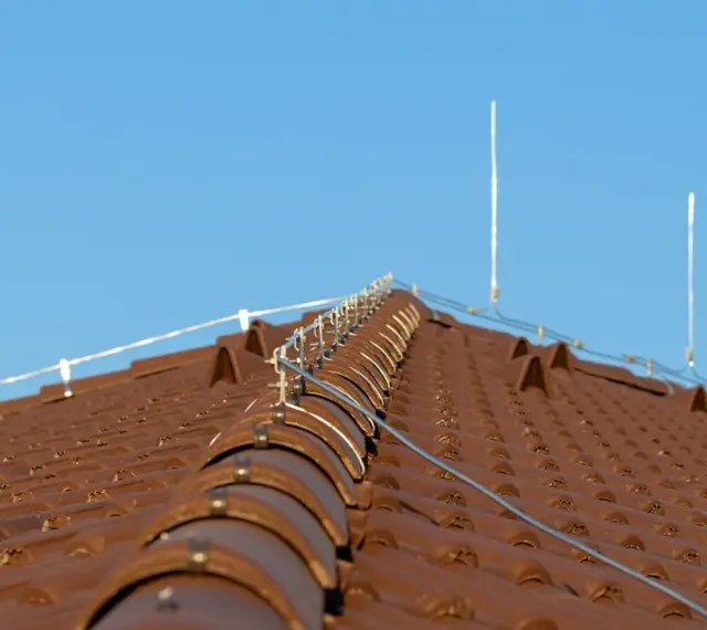 Nowy dach z brązowej dachówki, na którym zamontowano nowoczesną instalację odgromową, chroniącą przed burzami.