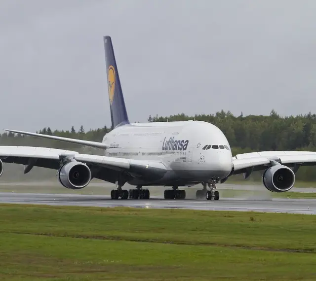 Lufthansa A380, największy samolot pasażerski, kołuje po mokrym pasie startowym.