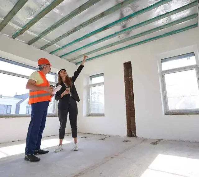 Inżynier i architektka omawiają projekt podwieszanego sufitu w nowym budynku.