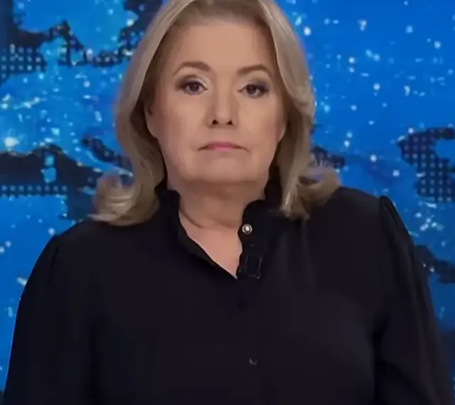 Kobieta w czarnej bluzce na tle mapy świata. Jej poważna mina sugeruje, że omawia ważne wiadomości, które wpływają na oglądalność.