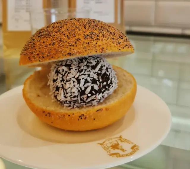En bulle med bulle: en chokladboll med kokosflingor inuti en delad bulle med vallmofrön.