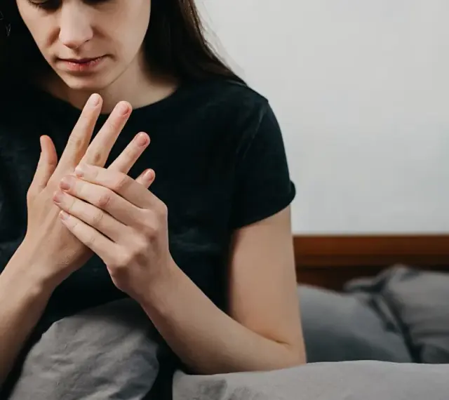 Kobieta masuje dłoń, odczuwając drętwienie rąk w nocy.