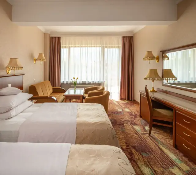 Pokój w hotelu Gołębiowski Wisła: dwa łóżka, kanapa, fotele, biurko i lustro.