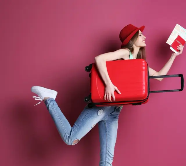 Kobieta z walizką i paszportem zastanawia się, ile kosztuje dodatkowy bagaż w Ryanair.