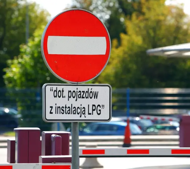 Znak B2 "zakaz wjazdu" z tabliczką informującą, że dotyczy pojazdów z instalacją LPG. Za znakiem widać szlaban i samochody.