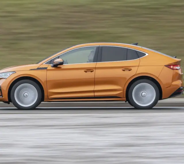 Pomarańczowy elektryczny SUV coupe w ruchu, widok z boku.