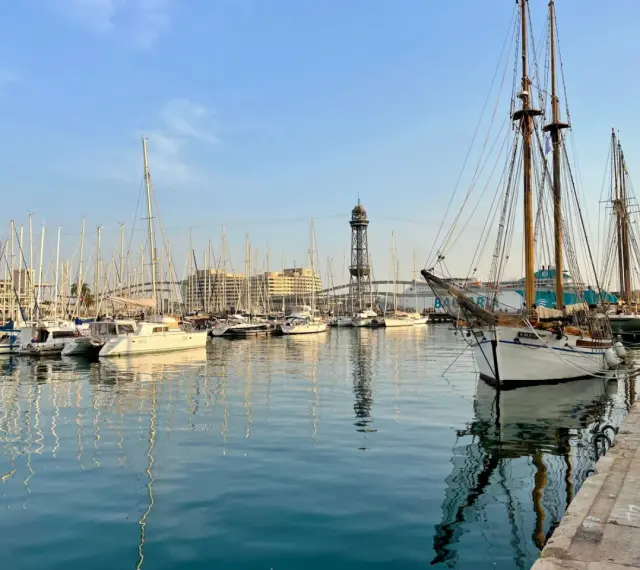 Port w Barcelonie, pełen żaglówek i statków, z wieżą widokową w tle. Czy w Barcelonie jest bezpiecznie? Tak, to spokojne miejsce.