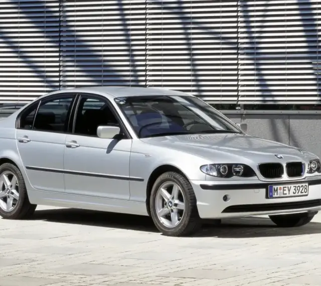 Srebrne e46 bmw sedan stoi przed nowoczesnym budynkiem z żaluzjami.