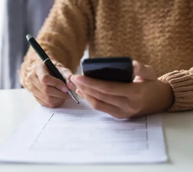 Kobieta z telefonem w dłoni wypełnia formularz, dokonując zgłoszenia darowizny online.