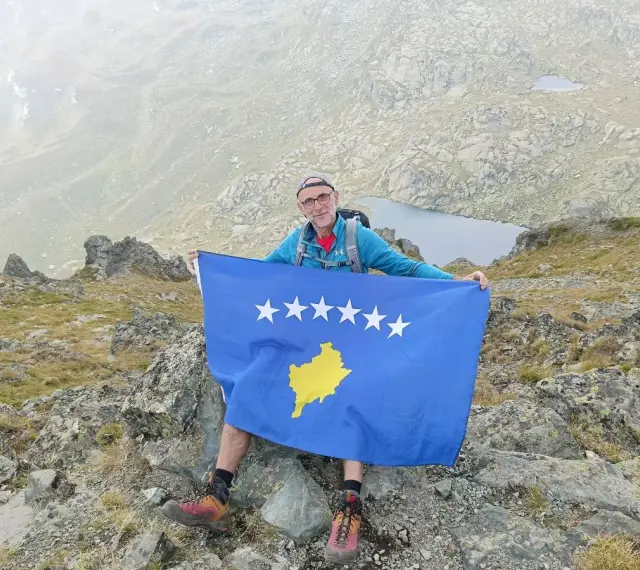 Mężczyzna z flagą najmłodszego państwa Europy, Kosowa, na szczycie góry.