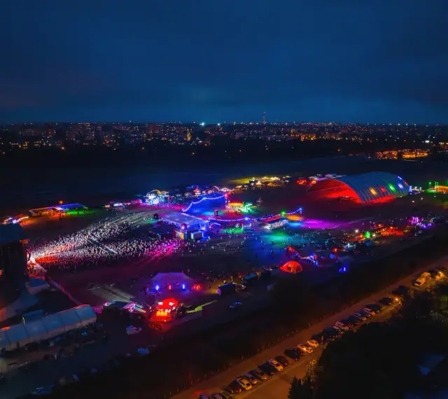 Nocne, kolorowe światła rozświetlają teren festiwalu na powietrzu. Tłumy bawią się pod wielkim, podświetlonym namiotem i na otwartych scenach.