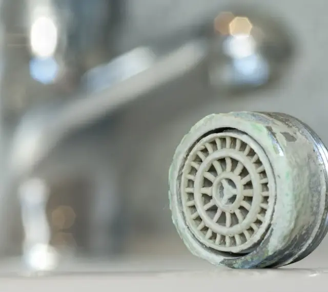 Zwapniony aerator kranu, który pokazuje, jak wyjąć sitko z kranu.