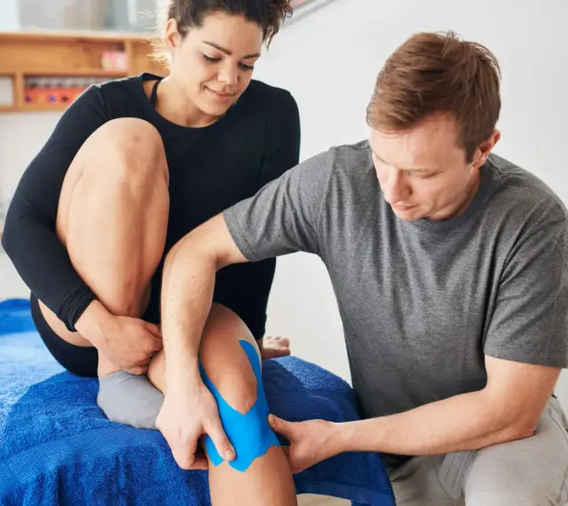 Mann legt blaues Tape auf Knie einer Frau. Eine Anleitung zum ultraschalltherapie selber machen könnte hier nützlich sein.