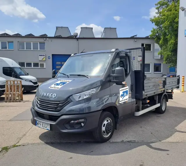 Szary Iveco z otwartą skrzynią ładunkową, idealny do wynajem wywrotki do 3,5 tony. Na drzwiach logo "Wypożyczalnia Moto-Partner".