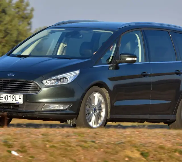 Ciemnozielony Ford Galaxy MK3 w ruchu, z polską tablicą rejestracyjną WE 019LF, przemierza wiejskie drogi.