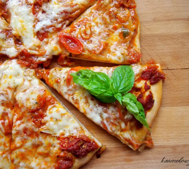 Szybki przepis na ciasto do pizzy: pyszna, domowa pizza z pomidorami i mozzarellą, ozdobiona świeżą bazylią.