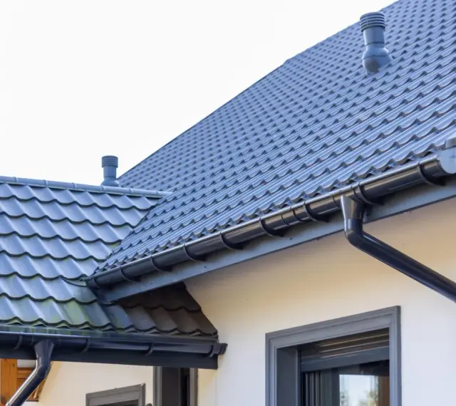 Szary dach z dachówki ceramicznej, system rynnowy. Sprawdź aktualną dachówka ceramiczna cena za m2.