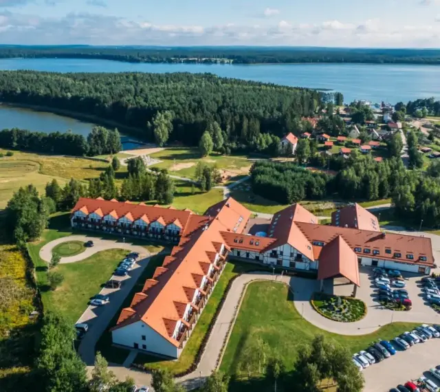 Malowniczy widok na Mikołajki Resort Spa z lotu ptaka, otoczony lasami i jeziorem. Idealne miejsce na relaks.