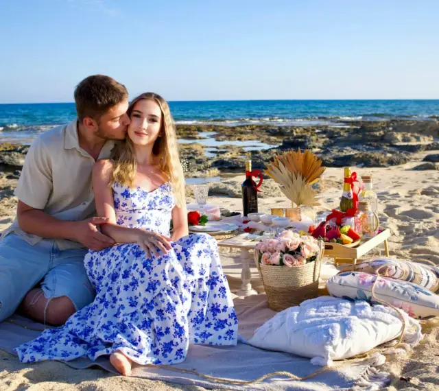 Romantyczny piknik na plaży podczas wakacji na Cyprze. Para cieszy się chwilą przy winie i owocach, z widokiem na morze.