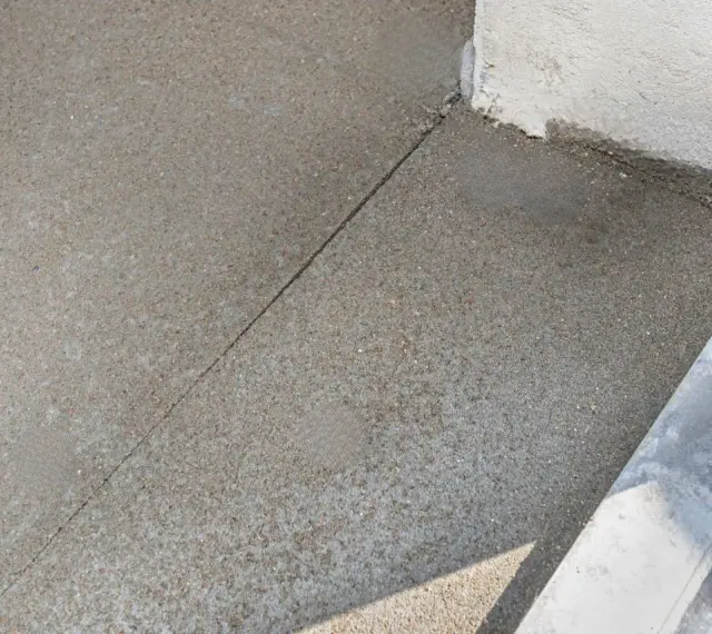 Dylatacja betonu na zewnątrz, widoczna linia podziału na świeżo wylanej nawierzchni, zapobiegająca pękaniu.