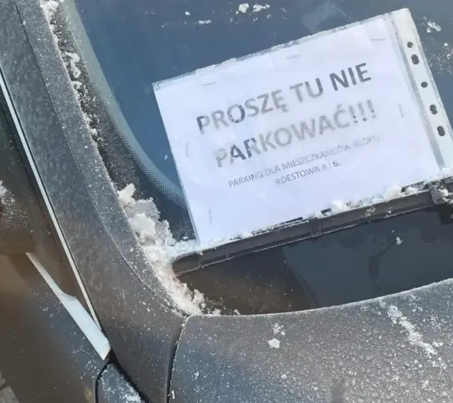 Na przedniej szybie samochodu, pokrytej szronem, widnieje kartka z napisem "Proszę tu nie parkować!!! Parking tylko dla mieszkańców bloku".