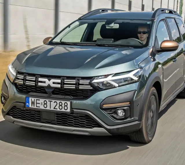 Dacia Jogger w zielonym kolorze jedzie po drodze. Sprawdź atrakcyjną dacia jogger cena i wybierz swój wymarzony samochód.