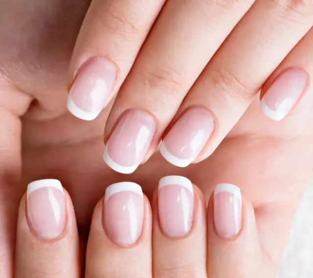 Dłonie z idealnym french manicure, gdzie białe końcówki paznokci lśnią jak tytanowe paznokcie.