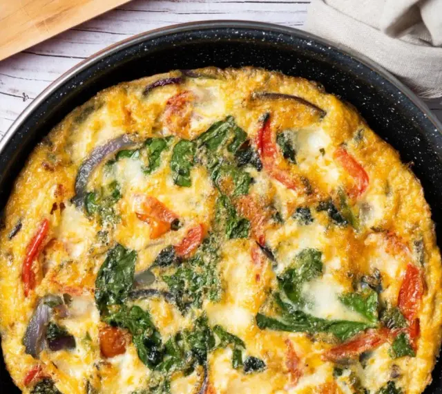 Pyszny omlet z cukinią, pomidorami i szpinakiem, zapieczony w patelni. Idealny na śniadanie lub lekki obiad.