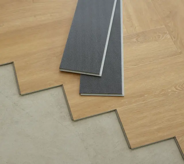 Szary podkład pod panele laminowane, gotowy do ułożenia na betonowej podłodze.