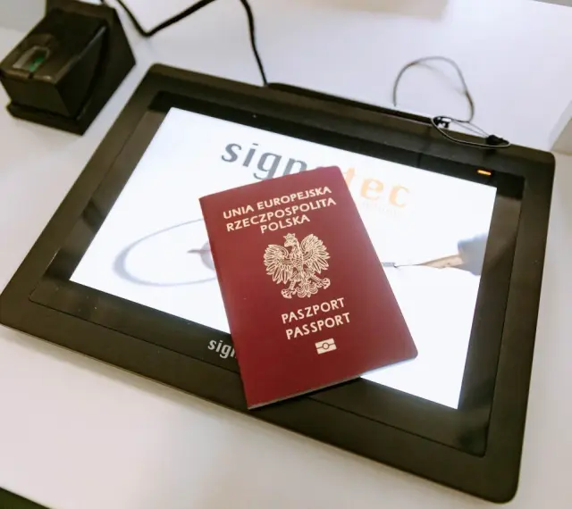 Polski paszport na ekranie tabletu w biurze paszportowym Włocławek. Obok skaner linii papilarnych.