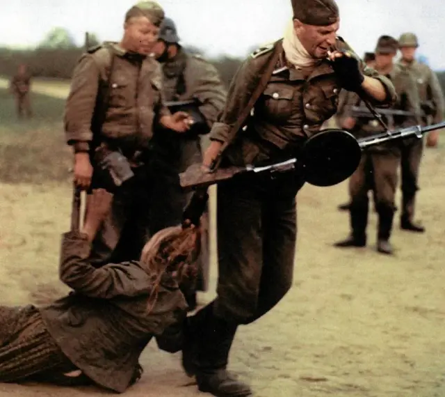Żołnierz z karabinem ciągnie kobietę za włosy. Obok stoi pies. Idź i patrz, co się dzieje.