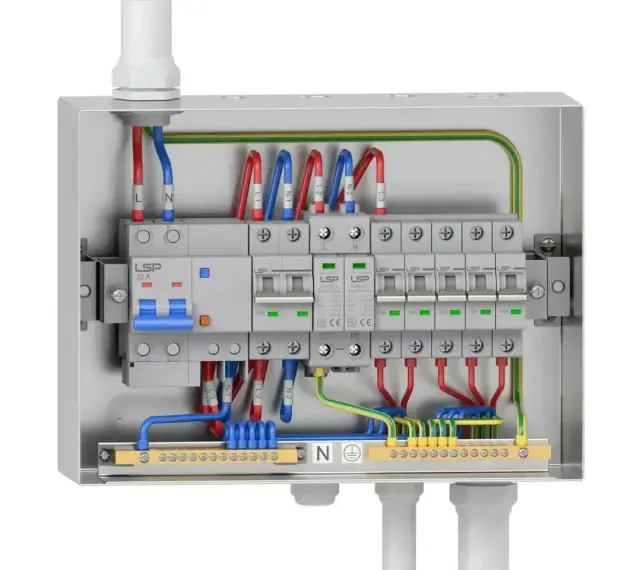Wnętrze metalowej skrzynki elektrycznej z wyłącznikami i przewodami. Widoczny kontakt natynkowy z bezpiecznikami i listwą zaciskową.