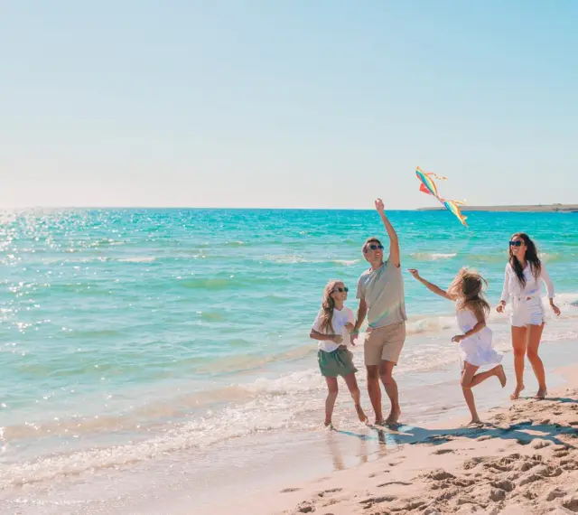 Rodzina puszcza latawiec na plaży. Idealne fajne miejsce na wakacje z dzieckiem w Polsce.