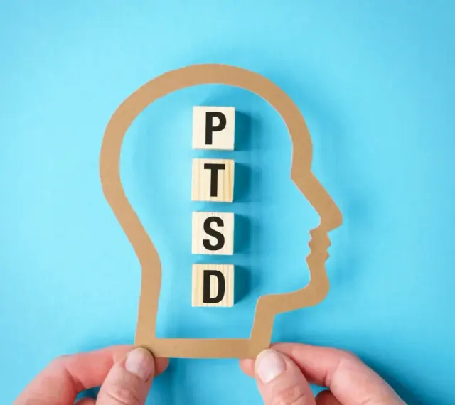 W głowie z papieru litery P, T, S, D układają się w słowo PTSD, symbolizując jego objawy.